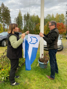 Ylituomarin sihteeri Anne Puikkonen ja ylituomari Juhani Kukkonen nostamassa SPJ:n viiriä salkoon.